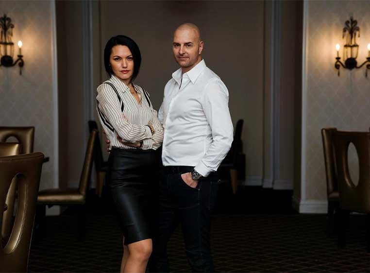 A professionally dressed couple posing for a camera